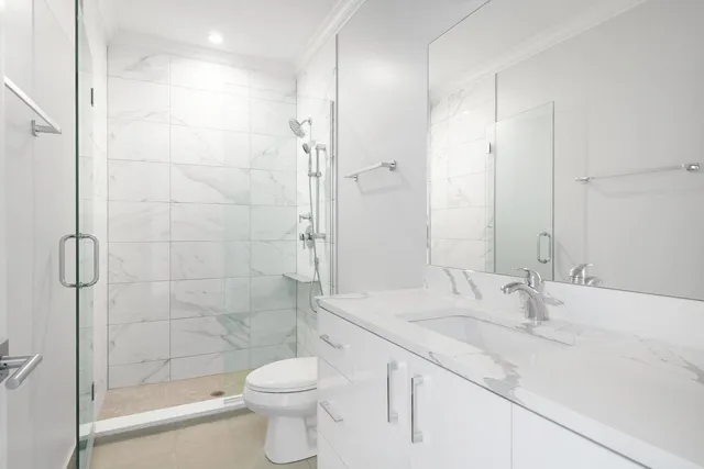a bathroom with a granite countertop sink a toilet and shower