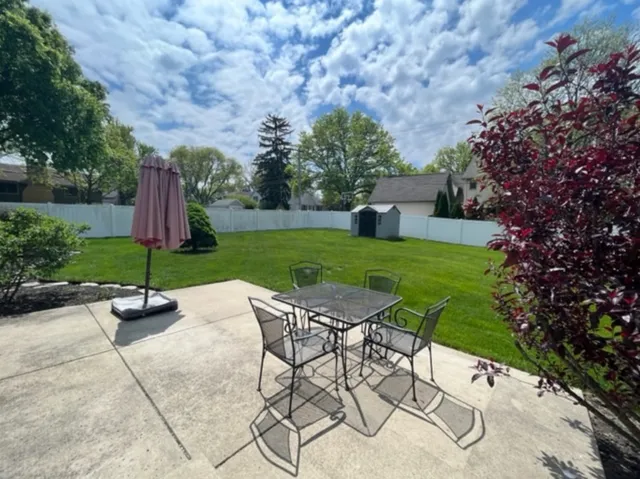 a view of a backyard with table and chairs under an umbrella