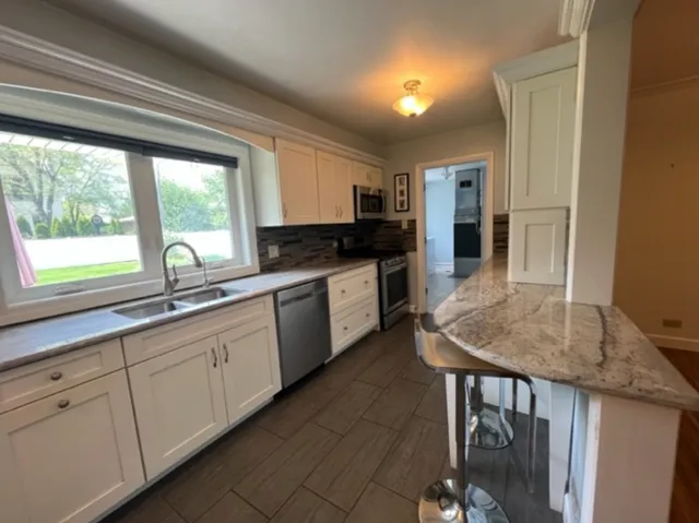 a kitchen with stainless steel appliances granite countertop a stove a sink and a microwave
