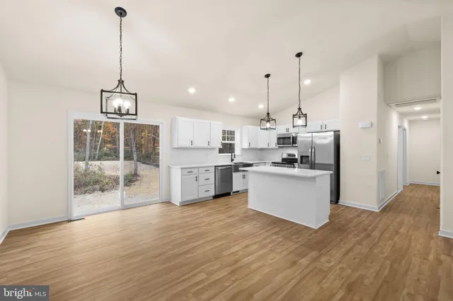 a kitchen with stainless steel appliances kitchen island wooden floors cabinets and dining table