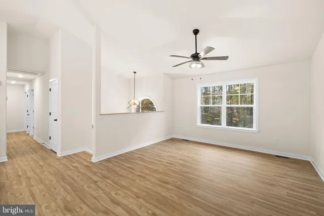 a view of room with window ceiling fan and wooden floor