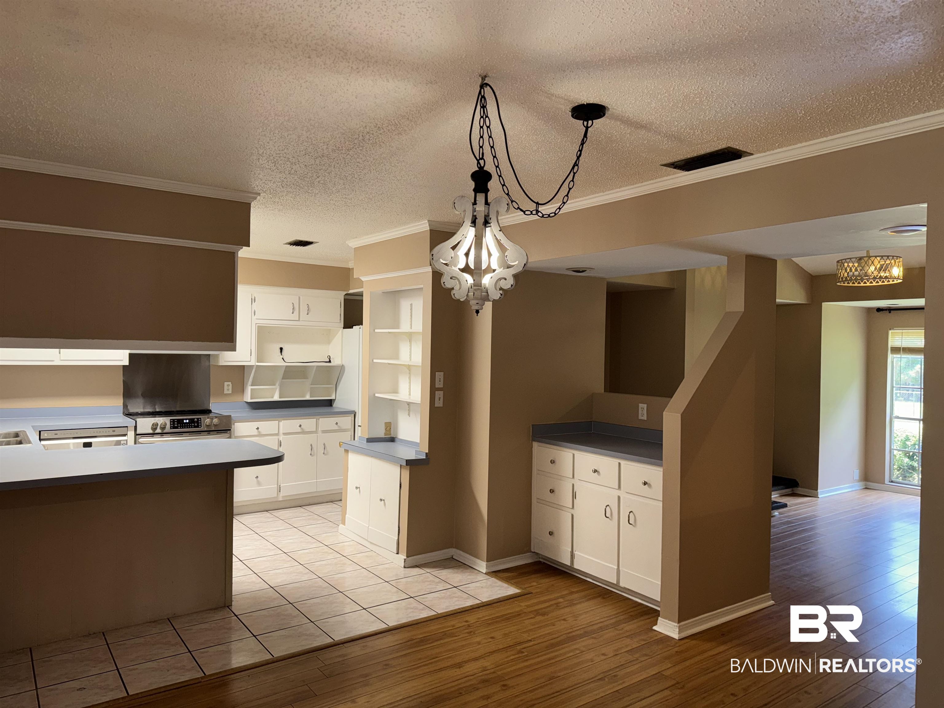 8070 Middle Ring Road Mobile, AL 36619 - Photo 10 of 26 Kitchen with light wood-type flooring, ornamental molding, white cabinets, a textured ceiling, and pendant lighting