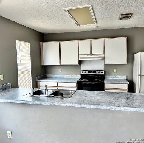 a kitchen with stainless steel appliances granite countertop a sink a stove and a refrigerator