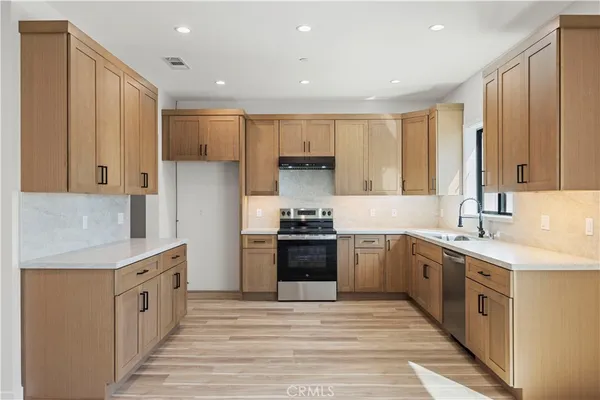 a large kitchen with stainless steel appliances granite countertop a stove a sink and a refrigerator