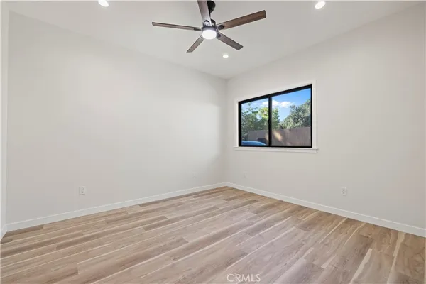 an empty room with wooden floor ceiling fan and windows