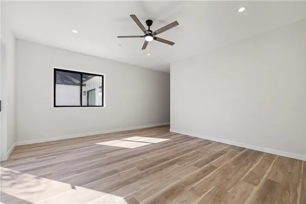 an empty room with wooden floor and a ceiling fan
