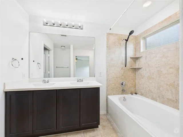 a bathroom with a bathtub a double vanity sink and mirror