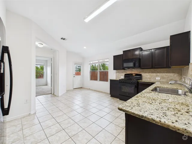 a large kitchen with stainless steel appliances kitchen island granite countertop a refrigerator and a sink