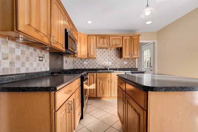 307 Oakwood Road Vernon Hills, IL 60061 - Photo 12 of 28 a kitchen with stainless steel appliances granite countertop a sink a stove and a refrigerator