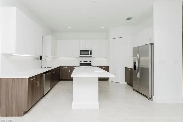 a kitchen with kitchen island a counter top space a sink stainless steel appliances and cabinets