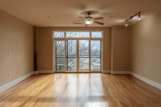 a view of an empty room with wooden floor and a window