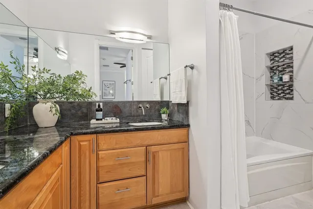 a bathroom with a granite countertop sink a mirror and shower