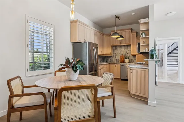 a kitchen with a dining table chairs and refrigerator