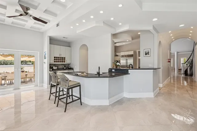 a kitchen with stainless steel appliances kitchen island granite countertop a stove a sink a refrigerator and white cabinets with wooden floor