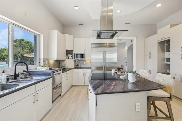 a kitchen with kitchen island granite countertop a sink a counter top stainless steel appliances and cabinets