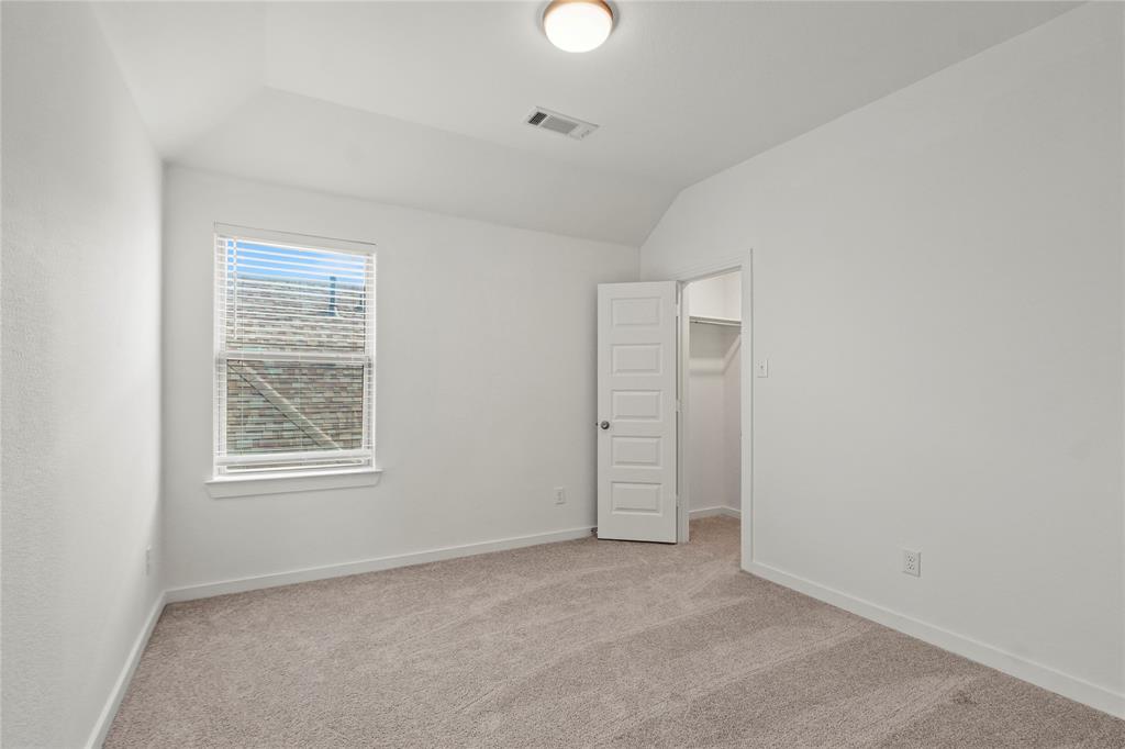 1805 Lockhart Drive Forney, TX 75126 - Photo 16 of 22 Unfurnished bedroom with a spacious closet, light carpet, and lofted ceiling