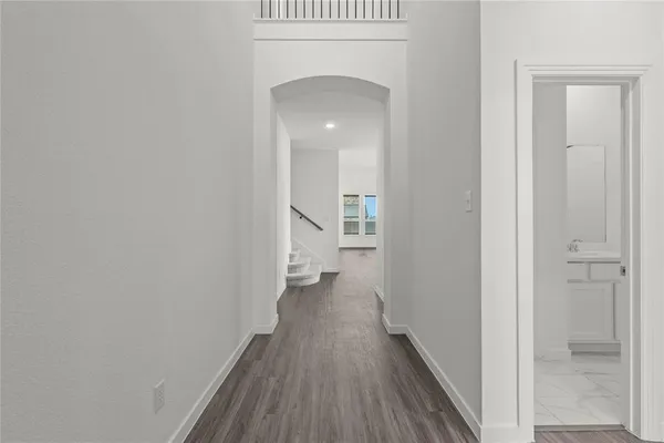a view of a hallway with wooden floor and a bathroom