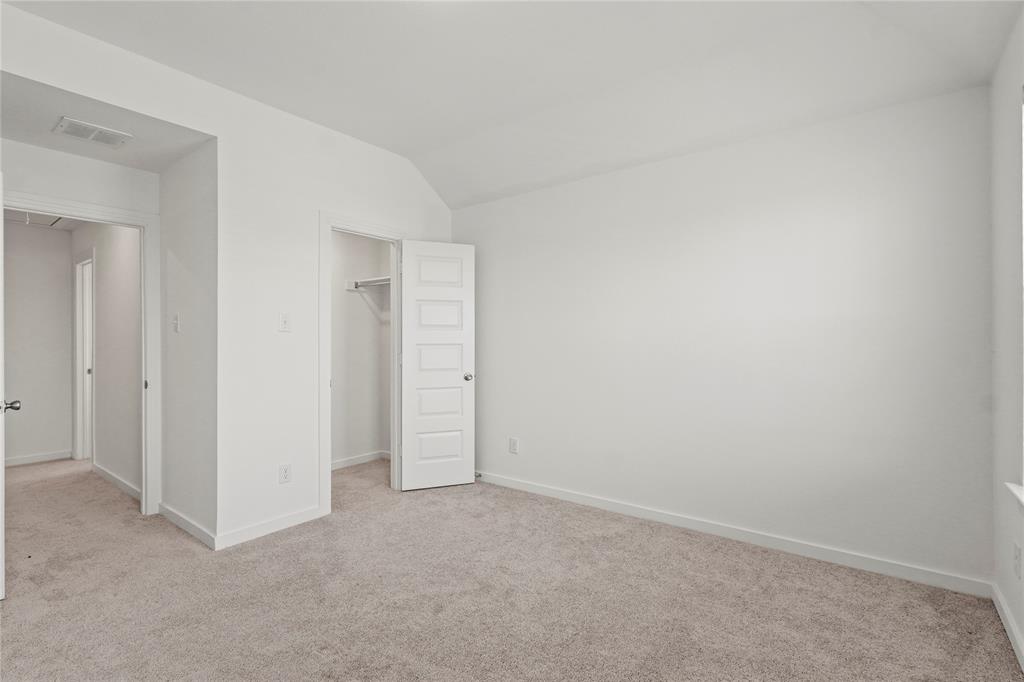 1805 Lockhart Drive Forney, TX 75126 - Photo 7 of 22 Unfurnished bedroom with a walk in closet, lofted ceiling, and light colored carpet
