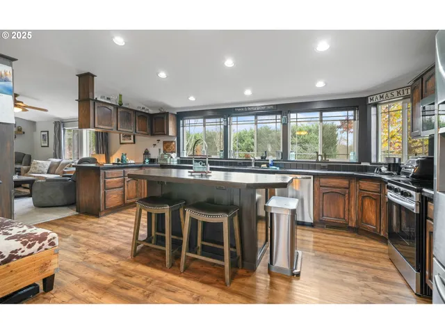 a kitchen with stainless steel appliances granite countertop a stove a sink a microwave a refrigerator and cabinets