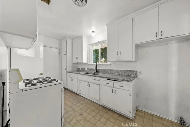 a kitchen with granite countertop a sink stove and cabinets