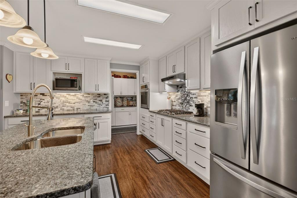 6249 South Esmeralda Terrace Lecanto, FL 34461 - Photo 16 of 61 a kitchen with stainless steel appliances granite countertop a refrigerator a stove a sink dishwasher and white cabinets with wooden floor