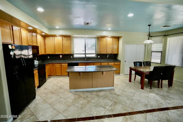 a kitchen with stainless steel appliances granite countertop a stove a sink a oven a dining table and chairs
