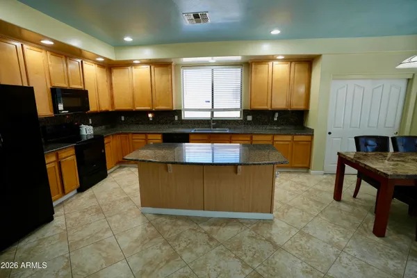 a kitchen with stainless steel appliances granite countertop a stove top oven a sink dishwasher a dining table and chairs with wooden floor