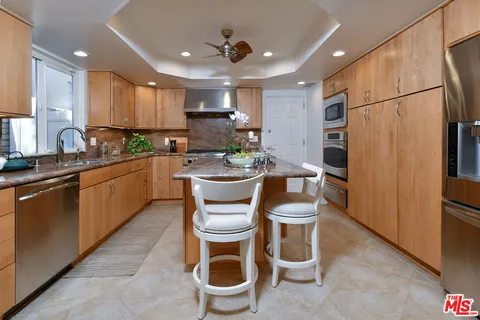 a kitchen with kitchen island granite countertop a sink stainless steel appliances and cabinets