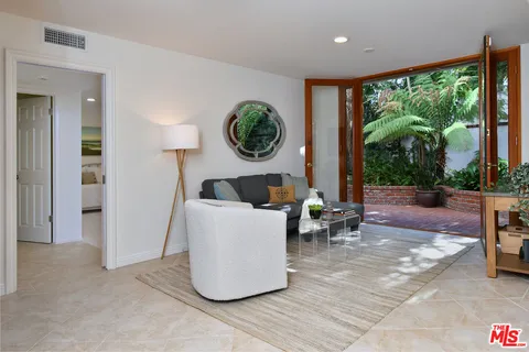 a view of a patio with table and chairs potted plants and large tree