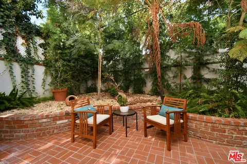 a backyard of a house with table and chairs under an umbrella