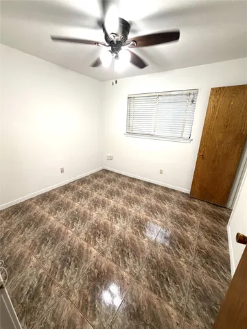 a view of a big room with wooden floor and chandelier fan