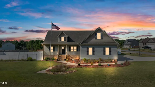 a front view of a house with a garden and lake view