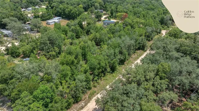 an aerial view of residential houses with outdoor space and trees
