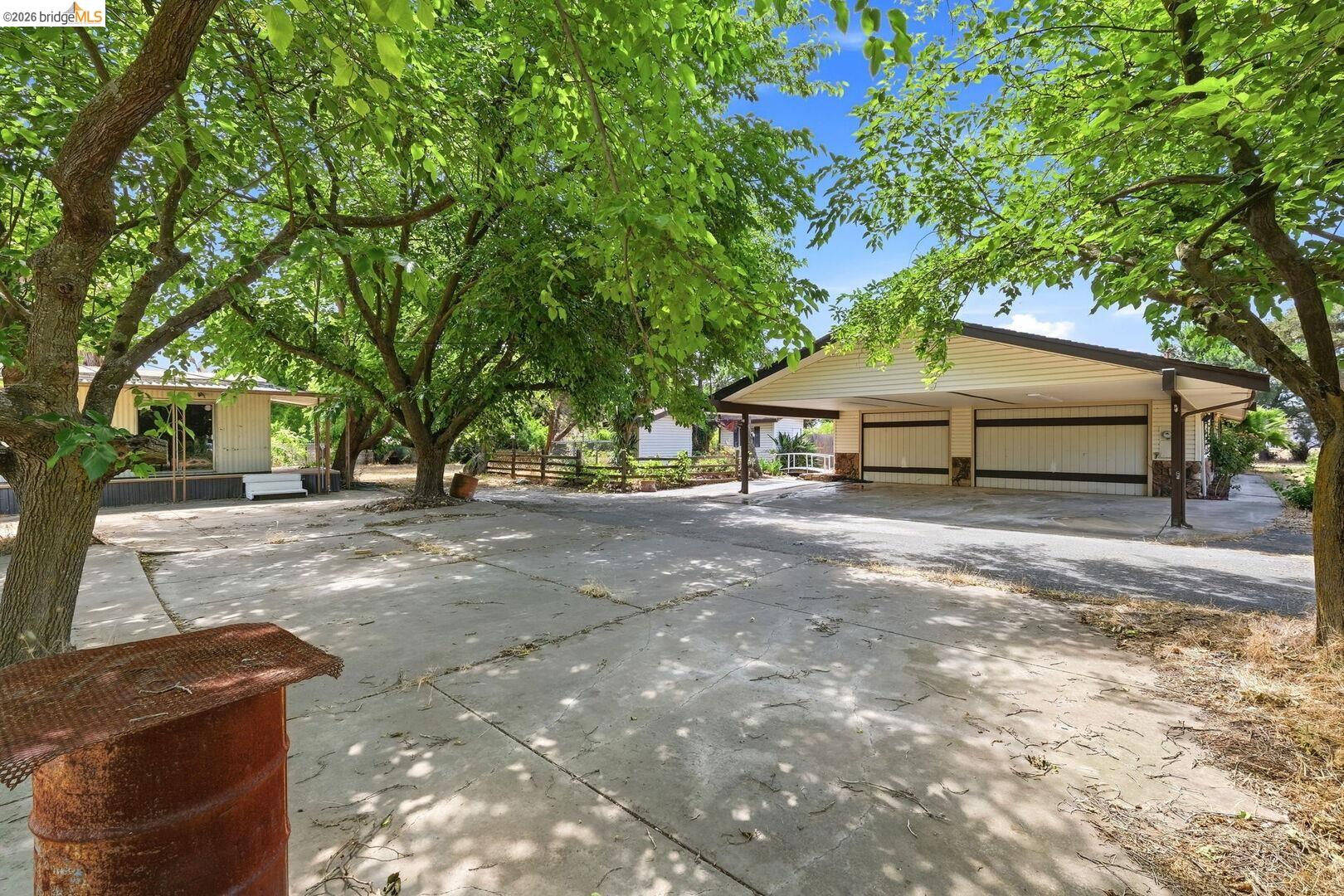 1590 Sunset Road Brentwood, CA 94513 - Photo 36 of 45 Multi-car carport with a light-colored siding facade, multiple garage bays, and mature shade trees