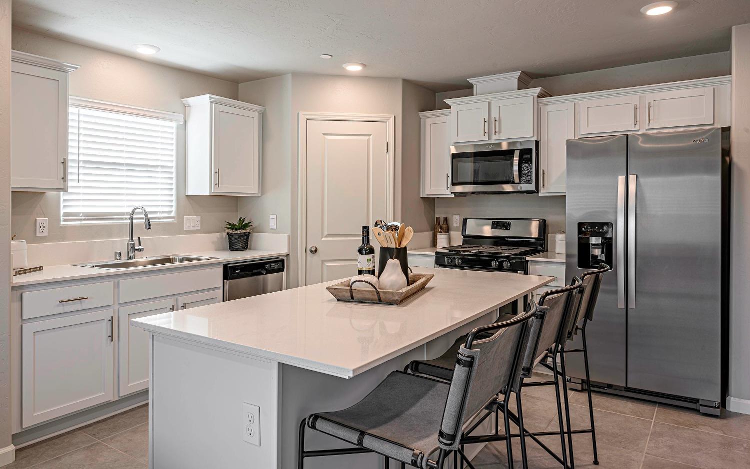 1553 Seneca Drive, Unit 86 Madera, CA 93637 - Photo 4 of 21 a kitchen with a refrigerator a stove a sink a stove a dining table and chairs