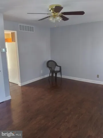 an empty room with a ceiling fan and wooden floor