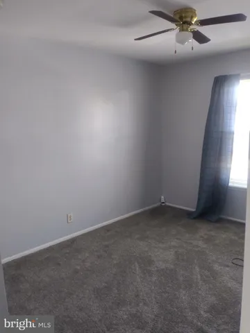 an empty room with a ceiling fan and window
