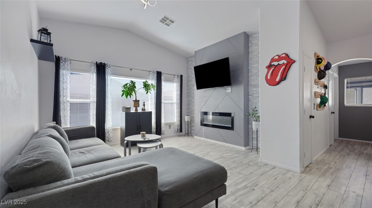 5940 High Steed Street, Unit 101 Henderson, NV 89011 - Photo 3 of 30 Living room with plenty of natural light, vaulted ceiling, light wood-look floors, a high end fireplace, and arched walkways