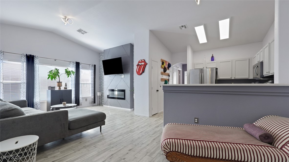 5940 High Steed Street, Unit 101 Henderson, NV 89011 - Photo 5 of 30 Living room featuring vaulted ceiling, light wood-look floors, and arched walkways