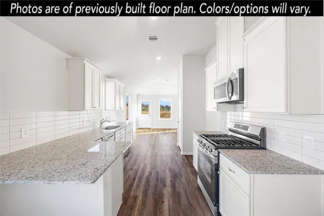 a kitchen with granite countertop a sink stove and cabinets