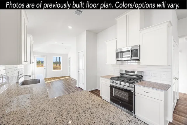 a kitchen with granite countertop a sink stove and cabinets