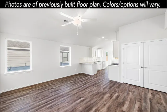 a view of kitchen and empty room with wooden floor