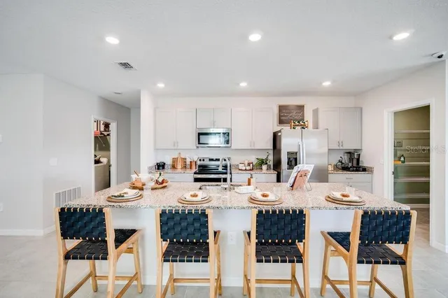 a living room with stainless steel appliances kitchen island granite countertop furniture a dining table chairs and a kitchen view