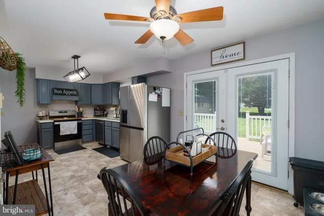 a dining room with stainless steel appliances kitchen island granite countertop furniture and a chandelier