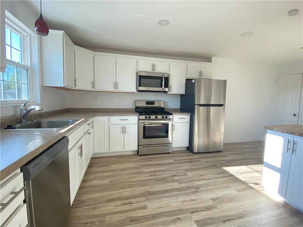 380 Vanadium Road Pittsburgh, PA 15243 - Photo 12 of 23 a kitchen with a refrigerator a stove top oven a sink and dishwasher with wooden floor