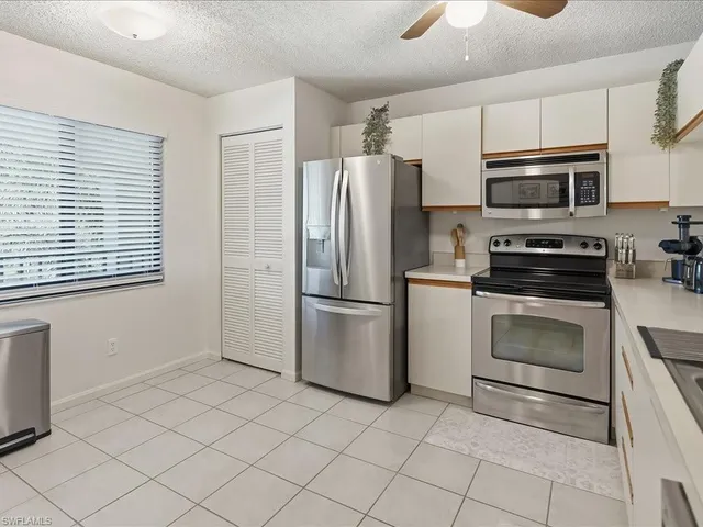 a kitchen with white cabinets stainless steel appliances and a window