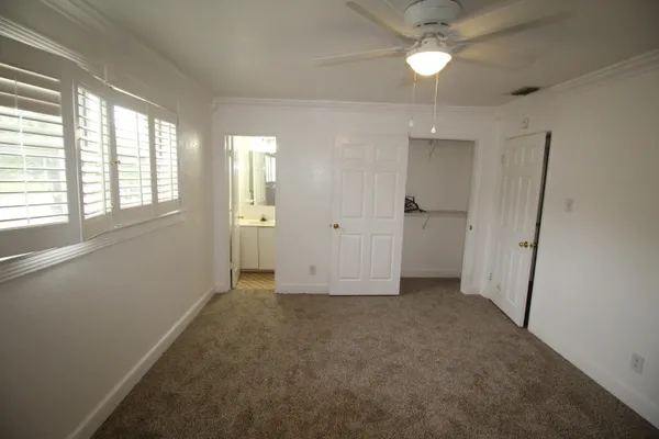 an empty room with chandelier fan and windows