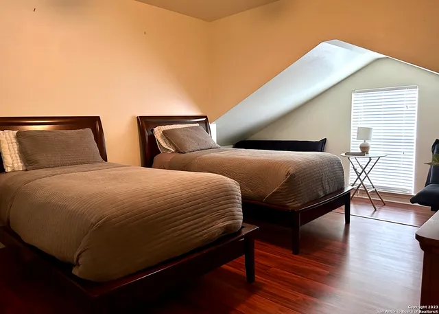 a bedroom with two beds and wooden floor