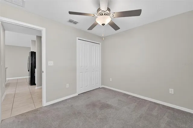 an empty room with a chandelier fan and windows