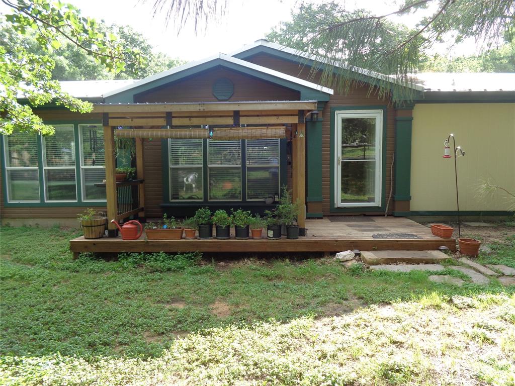 5525 Cedar Oaks Road Grandview, TX 76050 - Photo 2 of 40 Front exterior featuring a covered porch, wood-look siding, a white metal roof, and a glass-paneled entry door